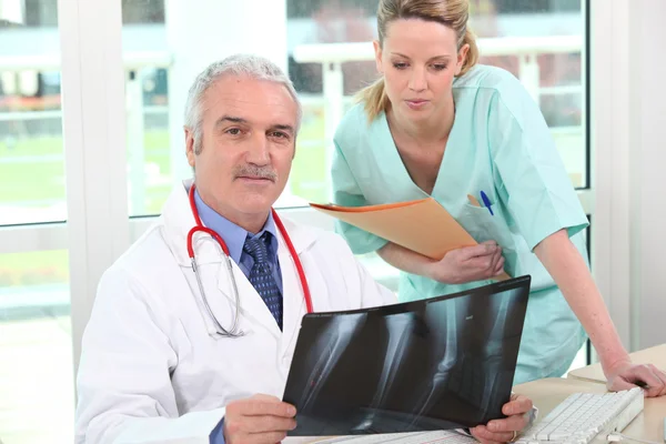 Läkaren undersöker en röntgenbild med sin assistent — Stockfoto