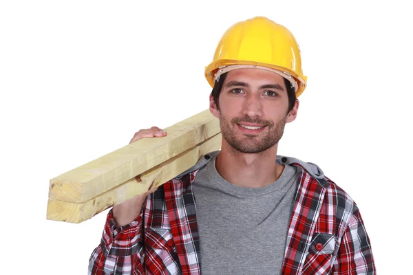 Carpenter carrying planks of wood over shoulder — Stock Photo, Image