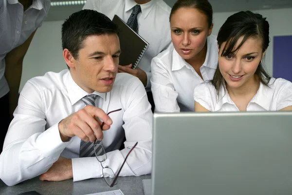 Neugierige Geschäftsleute schauen auf einen Laptop — Stockfoto
