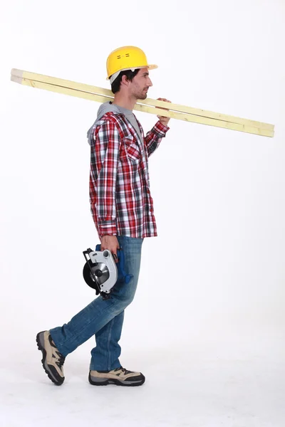 Tradesman portant des planches de bois et une scie circulaire — Photo