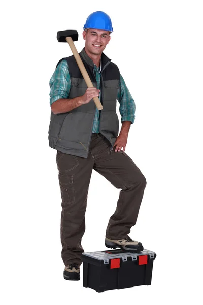 Hombre con martillo de trineo apoyando el pie en la caja de herramientas —  Fotos de Stock