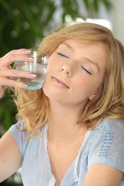 Mulher com os olhos fechados segurando um copo de água — Fotografia de Stock