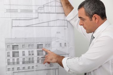 Architect examining a blueprint in detail clipart