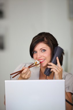 Woman eating sushi while talking on the phone clipart