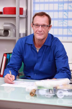 Plumber sitting at desk clipart