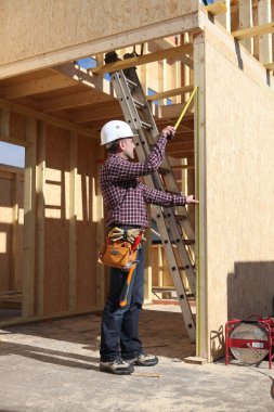 Contractor inspecting woodwork on house under construction clipart