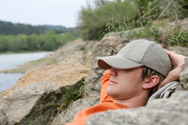 Man sleeping on the banks of a river — Stock Photo, Image