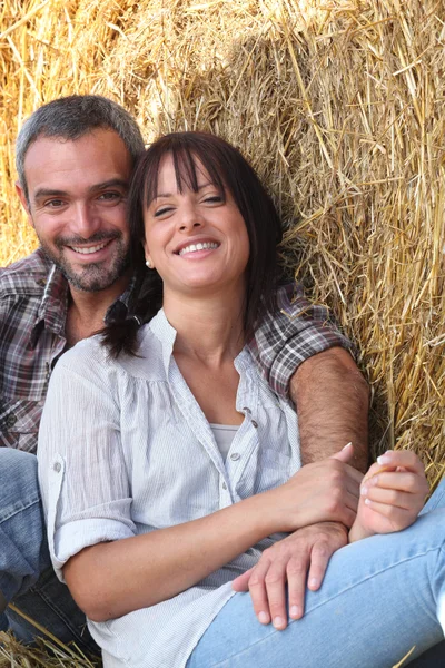 Casal de agricultores todos sorrisos posando no celeiro — Fotografia de Stock