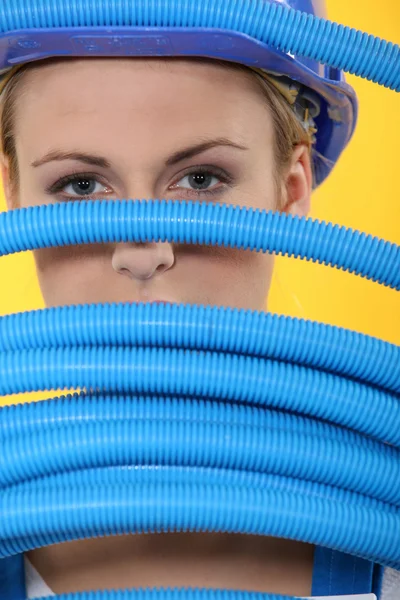 Trabalhadora da construção feminina espreitando através de tubos ondulados — Fotografia de Stock