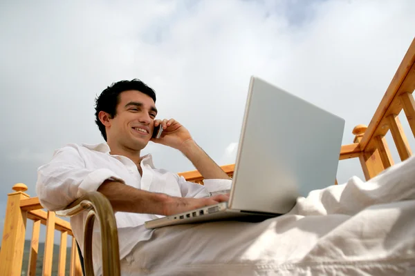 Adam bahçede oturup iken dizüstü bilgisayar ile rahatlatıcı — Stok fotoğraf