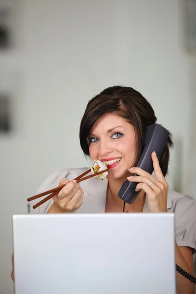 Frau isst Sushi, während sie telefoniert — Stockfoto