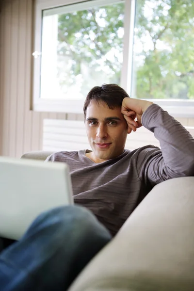 Young man on a sofa with a laptop — Stock Photo, Image