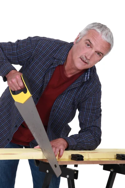 Äldre handyman sågning av trä — Stockfoto