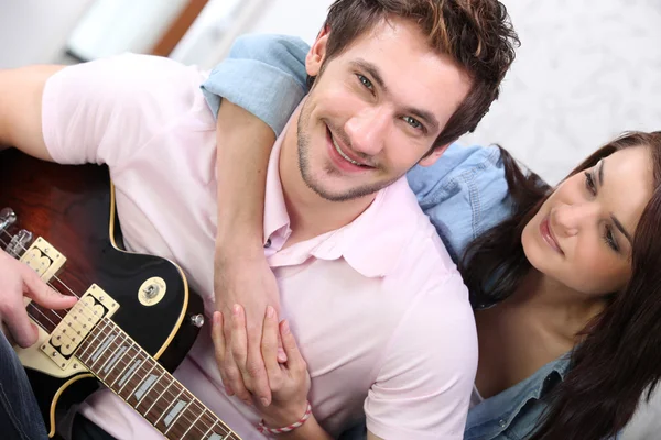 Νεαρό ζευγάρι παίζει μια κιθάρα στο σπίτι — Φωτογραφία Αρχείου