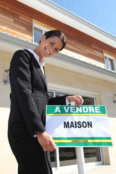 Agente inmobiliario apoyado en el letrero "Casa en venta" — Foto de Stock