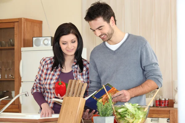 Young couple looking at a recipe book — Stock Photo, Image