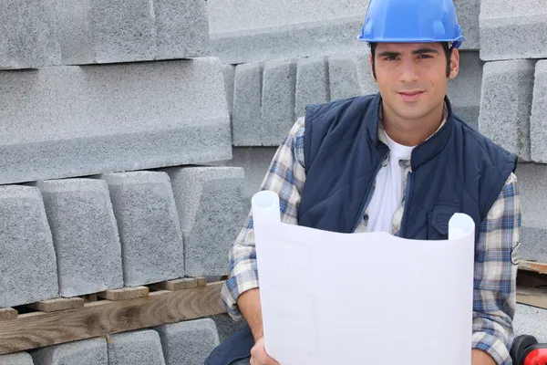 Bauarbeiter steht neben Paletten mit Betonrandsteinen und schaut nach — Stockfoto