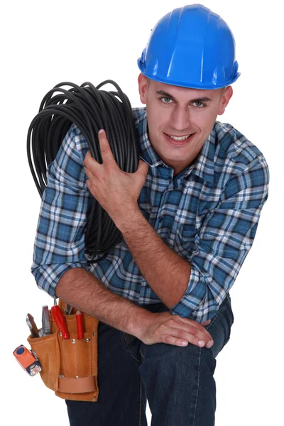 Tradesman carregando um cabo enrolada em torno de seu ombro — Fotografia de Stock