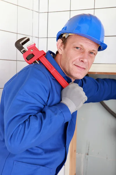 Loodgieter met een grote rode moersleutel gehouden over zijn schouder — Stockfoto