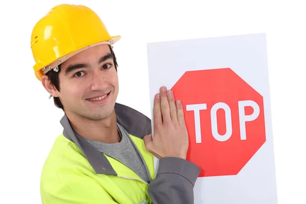 Road worker hiding the letter s of a stop sign — Stock Photo, Image