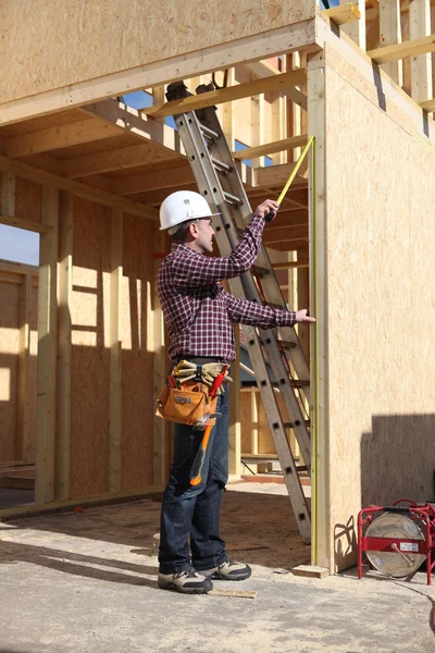 Підрядник оглядає деревообробку будинку, що будується — стокове фото