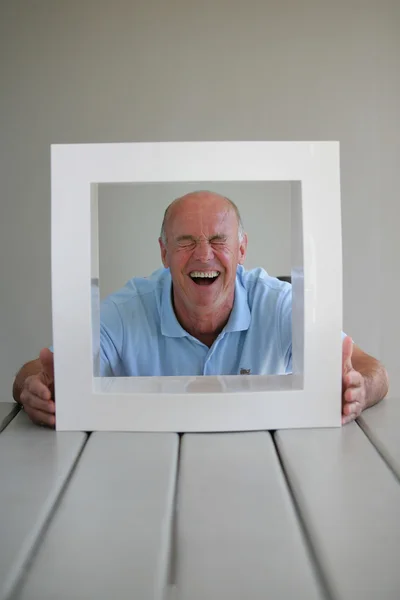 Senior looking through a picture frame — Stock Photo, Image