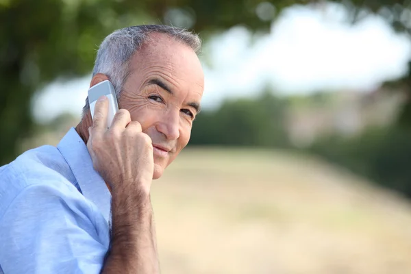 Senior walking outdoors and talking on the phone — Stock Photo, Image