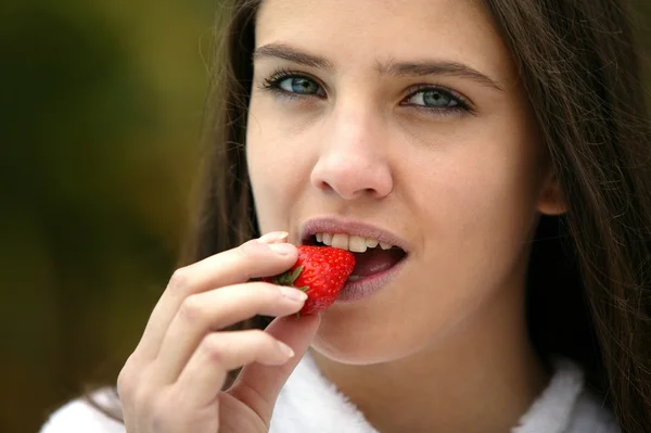 おいしいイチゴを食べるブルネット — ストック写真