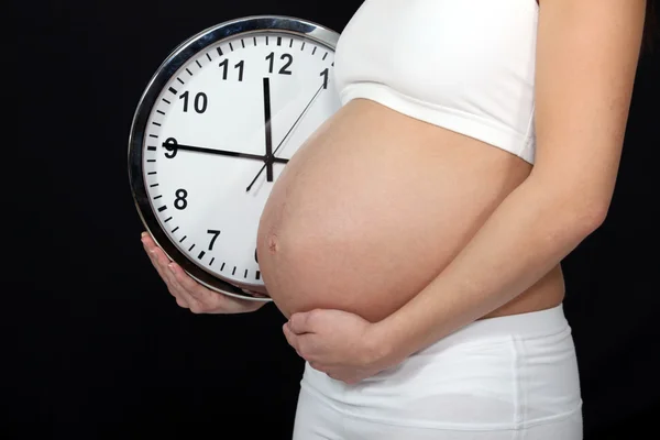 Uma mulher grávida segurando um relógio . — Fotografia de Stock