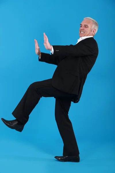 Middle-aged man in suit pushing invisible furniture — Stock Photo, Image