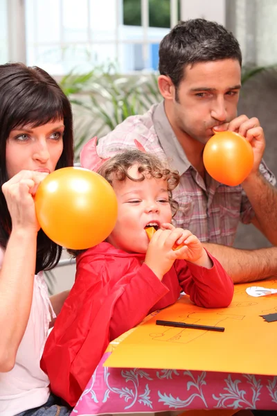 Family blowing balloons for a party — Stock Photo, Image