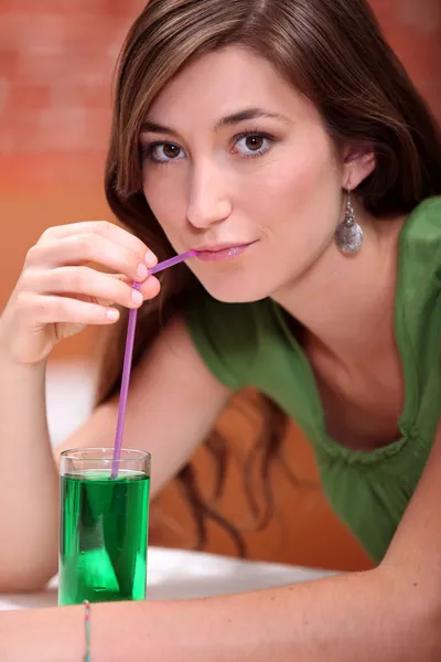 Νεαρή γυναίκα, ντυμένη στο πράσινο, πίνοντας μια λεμονάδα και εγκάρδια με ένα Δρ μέντα — Φωτογραφία Αρχείου
