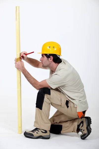 Comerciante marcando uma medição em uma prancha de madeira — Fotografia de Stock