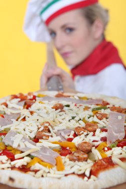 Female pizza cook putting a pizza in an oven clipart