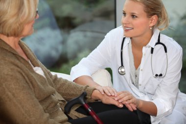 Medical assistant taking care of senior woman clipart