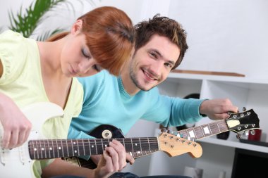 A guitar teacher and his female student clipart