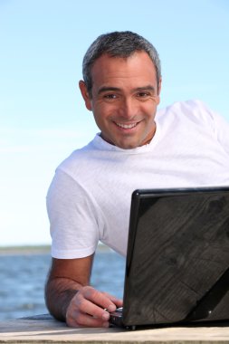 40 years old man doing computer behind the sea clipart