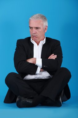 Grumpy man sitting on the floor clipart