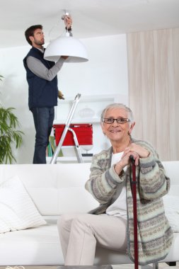 Young man fixing lamp for older woman clipart