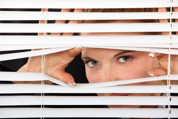 Mujer mirando a través de persianas — Foto de Stock