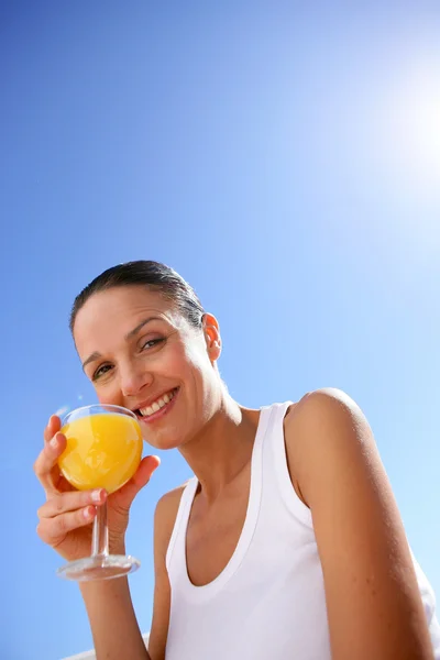 Весела жінка п'є апельсиновий сік — стокове фото