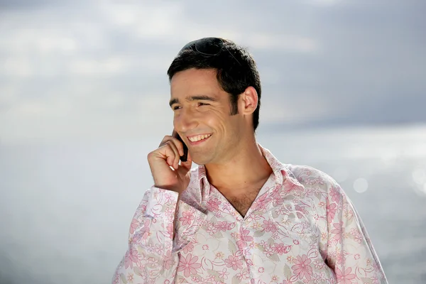 Uomo sorridente al telefono sulla costa — Foto Stock