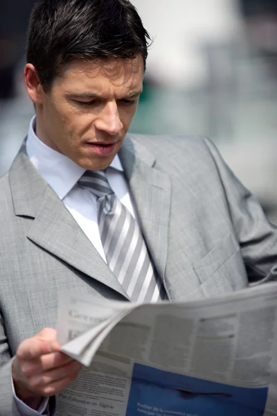 Businessman reading newspaper outdoors — Stock Photo, Image