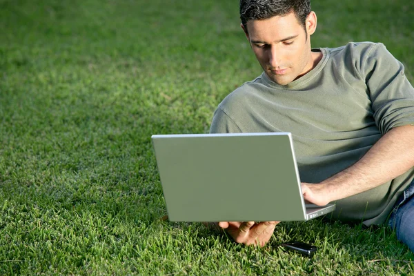 Uomo rilassante in campo con laptop — Foto Stock