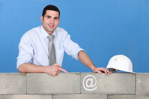 Affärsman som pekar på en vid tecken på en vägg — Stockfoto