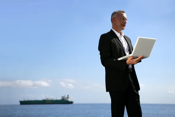 Empresario usando su portátil junto al borde del agua — Foto de Stock