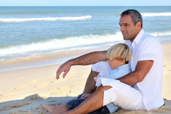 Padre e hijo sentados en una playa —  Fotos de Stock