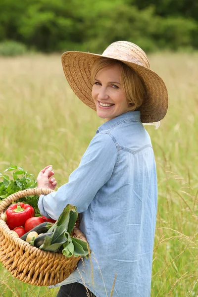 Mujer en el campo con cesta de verduras . — Foto de Stock