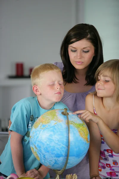 Mulher e crianças olhando para um globo — Fotografia de Stock