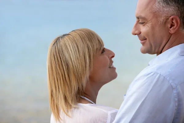 Зрелая пара улыбается на берегу моря — стоковое фото